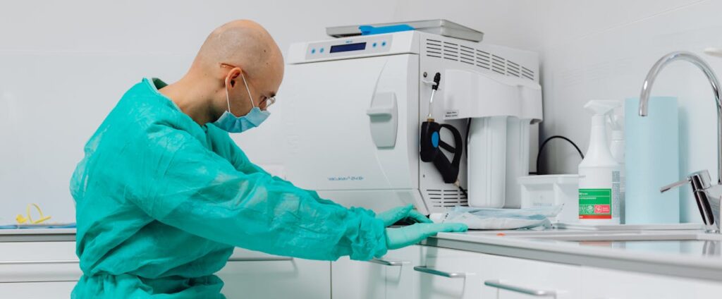 Dentist in sterile gloves and gown at dental office's cleaning area.