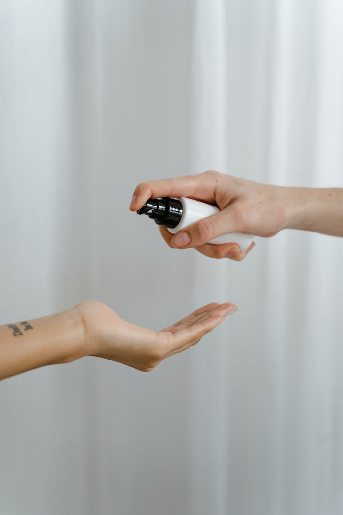 A close-up of a hand spraying sanitizer onto an open palm, promoting hygiene.